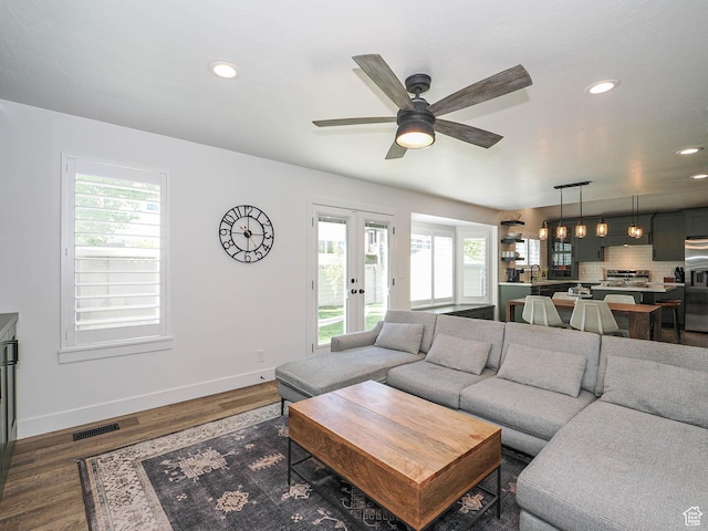 living area with healthy amount of natural light, dark wood-type flooring, a ceiling fan, baseboards, and recessed lighting