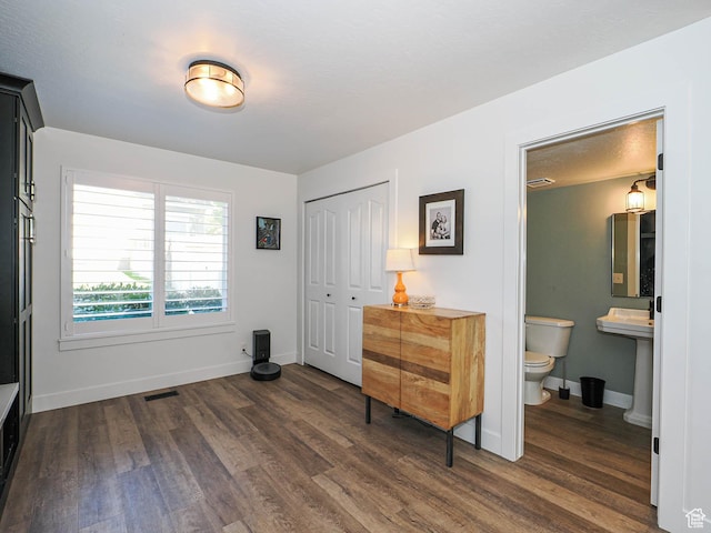 bedroom featuring dark wood-style flooring, a closet, baseboards, and ensuite bathroom