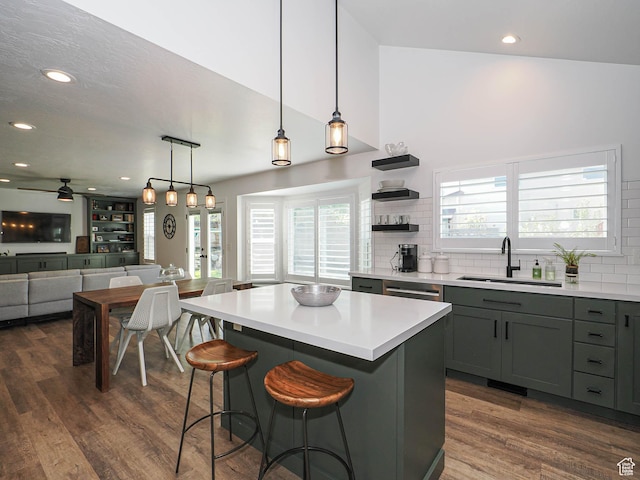kitchen featuring a sink, backsplash, dark wood finished floors, light countertops, and a kitchen bar