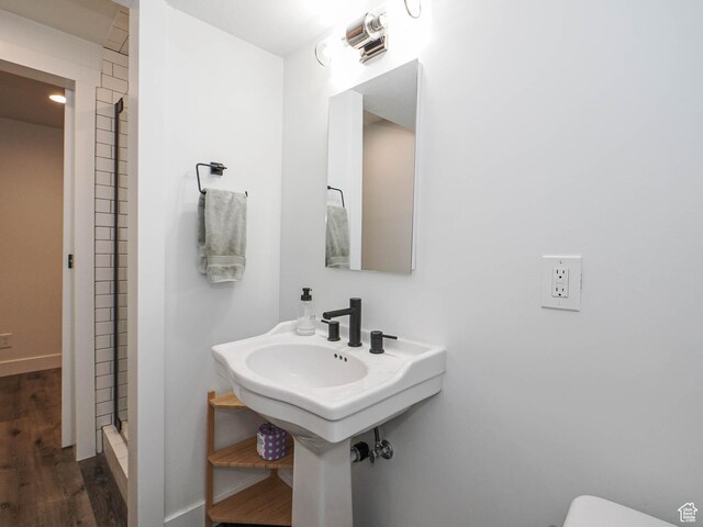 bathroom with a stall shower, baseboards, wood finished floors, and toilet