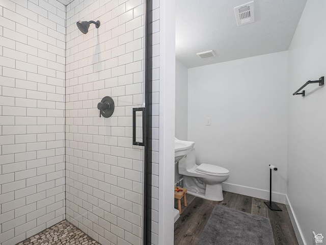 full bathroom with a shower stall, wood finished floors, toilet, and baseboards