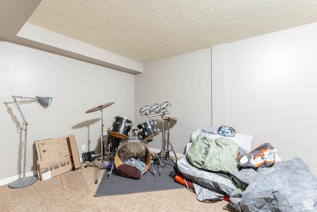 recreation room with baseboards and a textured ceiling