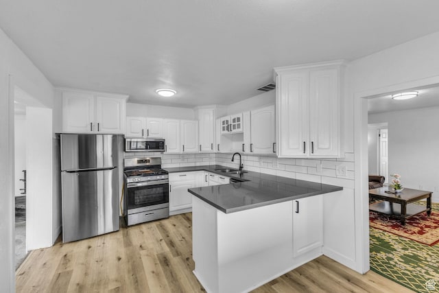 4587 W 5100 S, Kearns, UT 84118 - kitchen with stainless steel appliances, dark countertops, a peninsula, a sink, and white cabinets