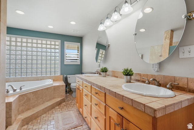bathroom featuring a bath, double vanity, toilet, and recessed lighting
