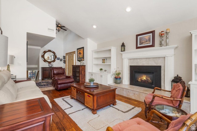 living room with ceiling fan, hardwood / wood-style floors, a tile fireplace, vaulted ceiling, and recessed lighting