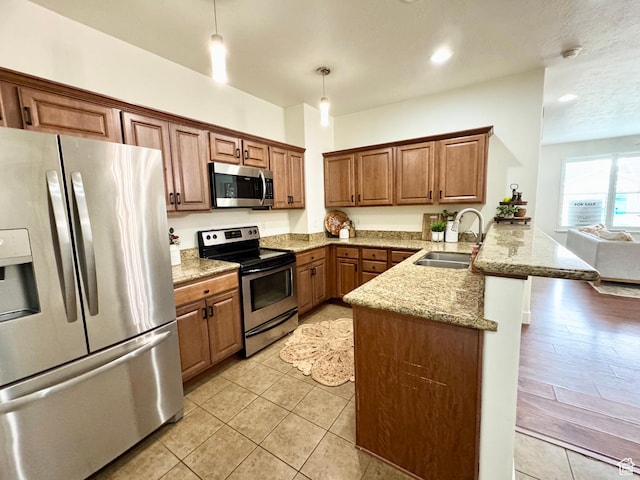 5062 W Valmont Way, Herriman, UT 84096 - kitchen featuring appliances with stainless steel finishes, a sink, a peninsula, hanging light fixtures, and brown cabinets
