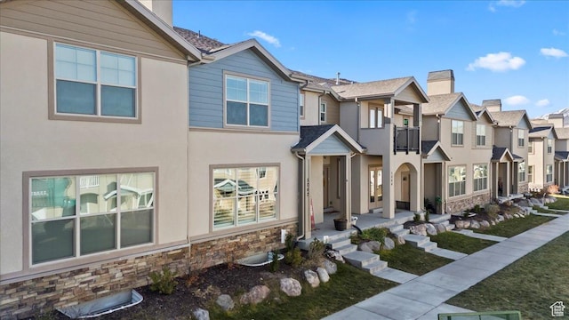 5062 W Valmont Way, Herriman, UT 84096 - townhome / multi-family property with stone siding, a residential view, a chimney, and stucco siding