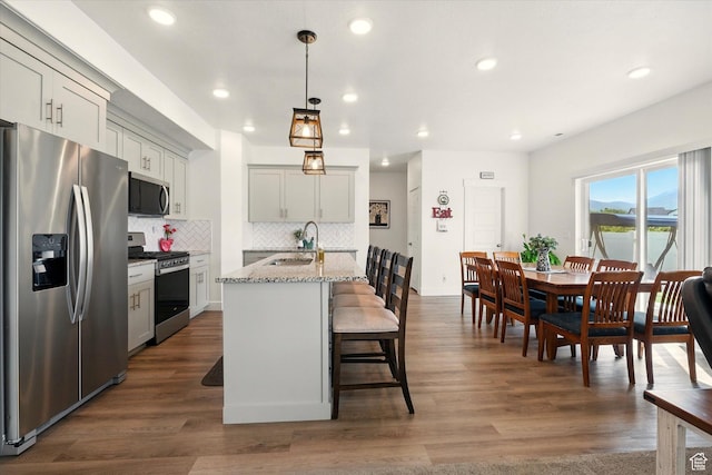 1412 W 1920 S, Logan, UT 84321 - kitchen featuring appliances with stainless steel finishes, a sink, decorative backsplash, a center island with sink, and a kitchen breakfast bar