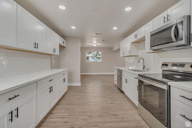 4098 W 5580 S, Salt Lake City, UT 84118 - kitchen with appliances with stainless steel finishes, a sink, baseboards, recessed lighting, and light wood-type flooring