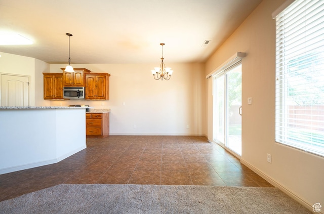 2710 W 410 N, Hurricane, UT 84737 - kitchen featuring stainless steel microwave, brown cabinets, a chandelier, dark tile patterned floors, and hanging light fixtures
