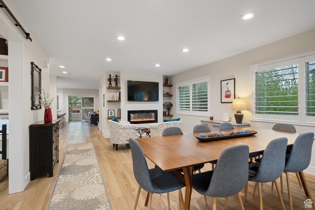 1288 E Foxcrest Ct, Park City, UT 84098 - dining area with a barn door, healthy amount of natural light, a glass covered fireplace, recessed lighting, and light wood finished floors