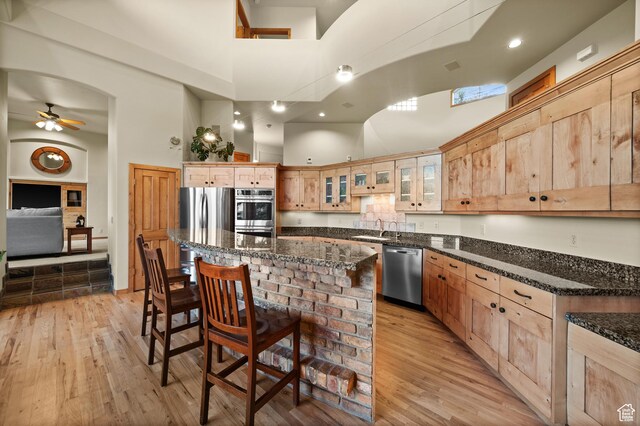 9266 Par Ct, Park City, UT 84098 - kitchen featuring stainless steel appliances, a high ceiling, a sink, ceiling fan, and a breakfast bar area