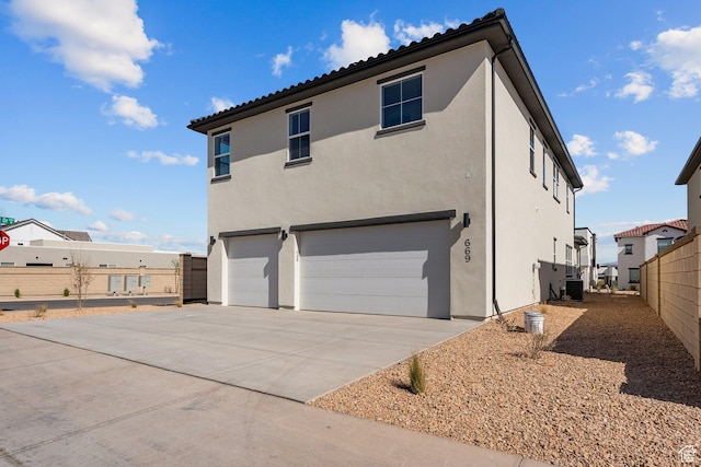 669 Juniper Hill Dr, St George, UT 84790 - rear view of property featuring an attached garage, stucco siding, central AC unit, and concrete driveway