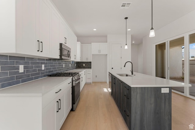 669 Juniper Hill Dr, St George, UT 84790 - kitchen featuring appliances with stainless steel finishes, a sink, backsplash, light wood finished floors, and white cabinets