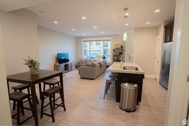 2729 W Linwood Ct, Salt Lake City, UT 84129 - kitchen featuring stainless steel refrigerator with ice dispenser, a sink, light wood-type flooring, recessed lighting, and a breakfast bar