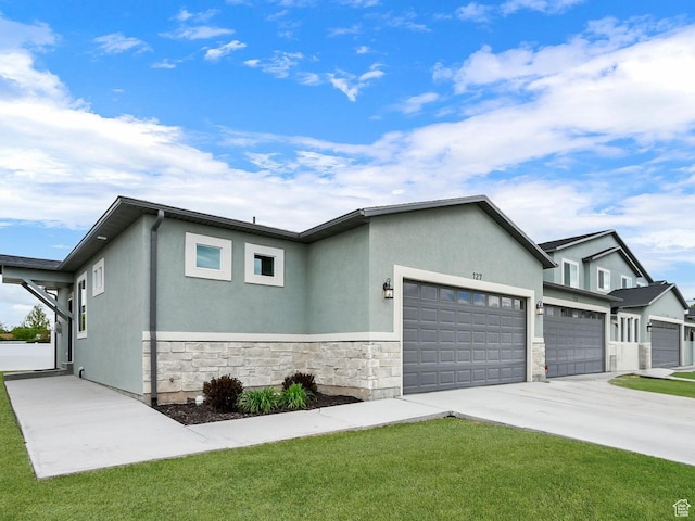 250 W 1200 S Unit 127, Tremonton, UT 84337 - view of front of property featuring an attached garage, stone siding, driveway, stucco siding, and a front yard