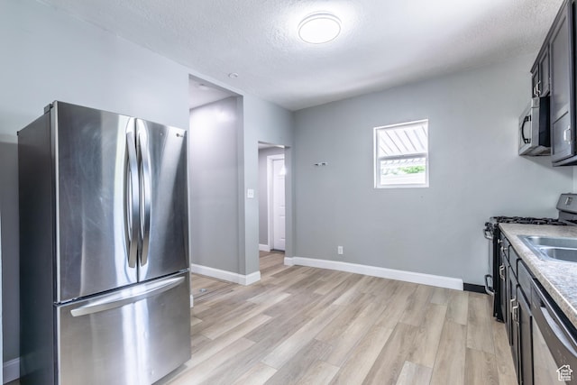 2665 S 8900 W, Magna, UT 84044 - kitchen featuring appliances with stainless steel finishes, a textured ceiling, light wood finished floors, light countertops, and baseboards