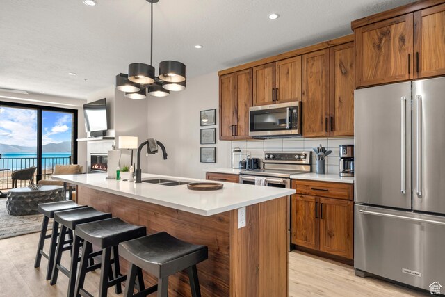 35 E 150 S Unit 202C, Garden City, UT 84028 - kitchen featuring appliances with stainless steel finishes, a sink, brown cabinetry, light wood finished floors, and recessed lighting