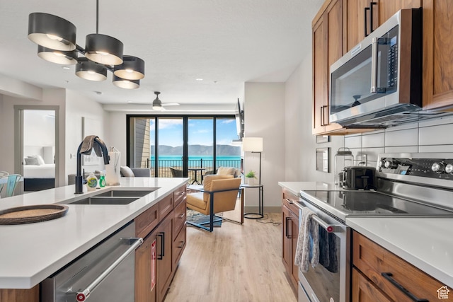 35 E 150 S Unit 202C, Garden City, UT 84028 - kitchen featuring stainless steel appliances, a sink, open floor plan, brown cabinets, and light wood-style floors