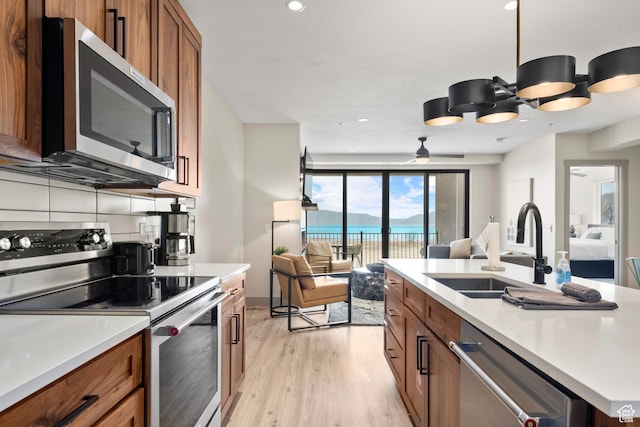 35 E 150 S Unit 202C, Garden City, UT 84028 - kitchen with appliances with stainless steel finishes, a sink, open floor plan, brown cabinetry, and light wood finished floors