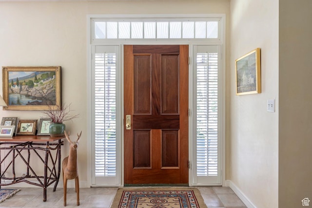 foyer featuring baseboards, plenty of natural light, and light tile patterned floors