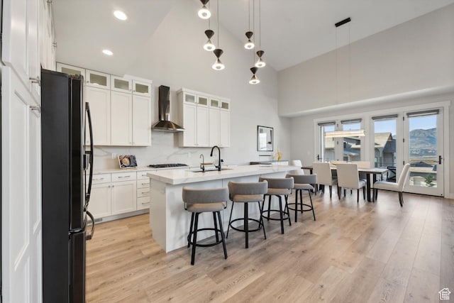 363 E Overlook Loop E Unit 22, Hideout, UT 84036 - kitchen featuring freestanding refrigerator, wall chimney range hood, high vaulted ceiling, light wood-style floors, and white cabinets