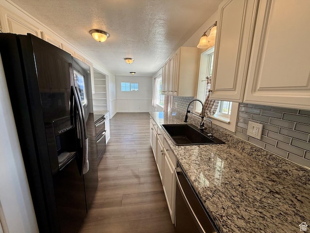 kitchen featuring black fridge, a sink, dark wood-style flooring, a textured ceiling, and backsplash