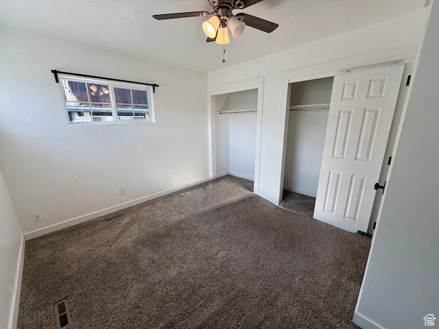 unfurnished bedroom featuring multiple closets, carpet floors, baseboards, and a ceiling fan