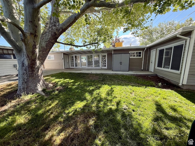 back of property with a yard, a patio area, and a chimney