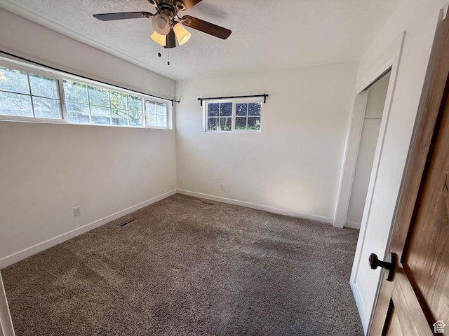 unfurnished bedroom featuring carpet floors, a textured ceiling, baseboards, and a ceiling fan