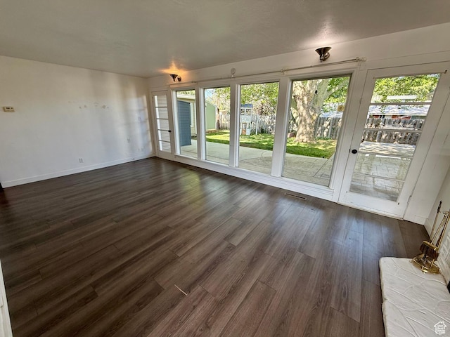 unfurnished living room featuring dark wood-style flooring and baseboards