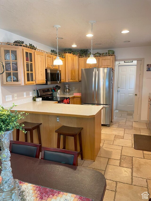 2285 S 450 W, Perry, UT 84302 - kitchen with stainless steel appliances, stone tile floors, a peninsula, light countertops, and glass insert cabinets