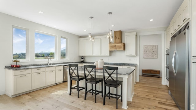 267 E Sandhill Dr, Saratoga Springs, UT 84045 - kitchen with appliances with stainless steel finishes, light wood-style floors, a kitchen bar, a sink, and a center island