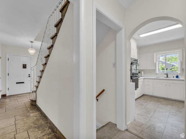 941 S Connor St E, Salt Lake City, UT 84108 - corridor featuring arched walkways, baseboards, a sink, stairway, and light stone finish flooring