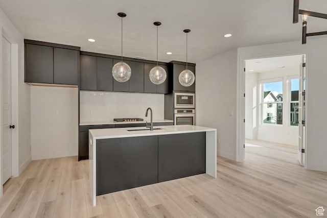 6904 W Lake Ave S Unit 213, South Jordan, UT 84009 - kitchen featuring appliances with stainless steel finishes, a sink, light wood-style floors, light countertops, and hanging light fixtures