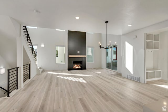 6904 W Lake Ave S Unit 213, South Jordan, UT 84009 - unfurnished living room featuring light wood-style flooring, a large fireplace, stairs, a chandelier, and recessed lighting