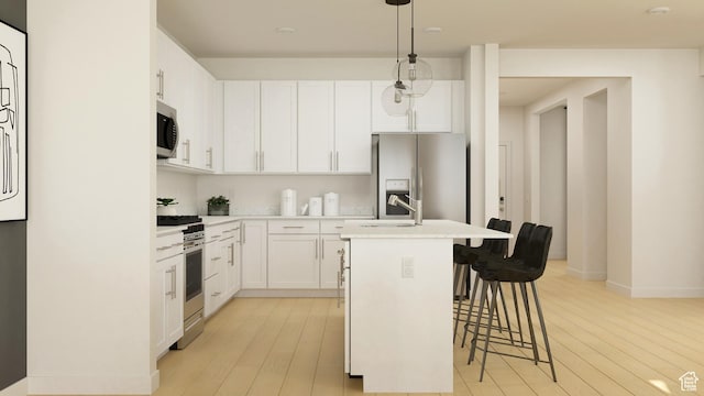 kitchen with appliances with stainless steel finishes, an island with sink, light wood-style flooring, and a breakfast bar