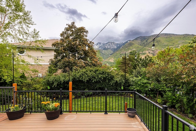 wooden terrace featuring a mountain view and a lawn