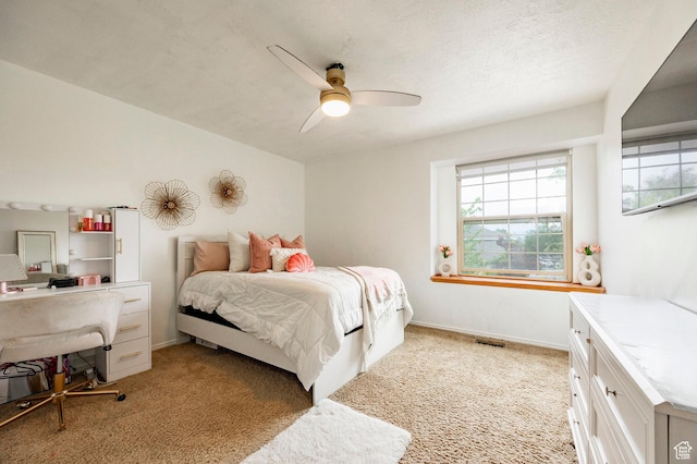 bedroom featuring light carpet, ceiling fan, baseboards, and an office area