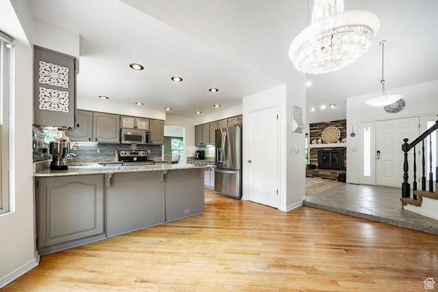 kitchen featuring appliances with stainless steel finishes, gray cabinets, a peninsula, recessed lighting, and baseboards