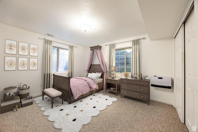 carpeted bedroom featuring multiple windows, a closet, and baseboards