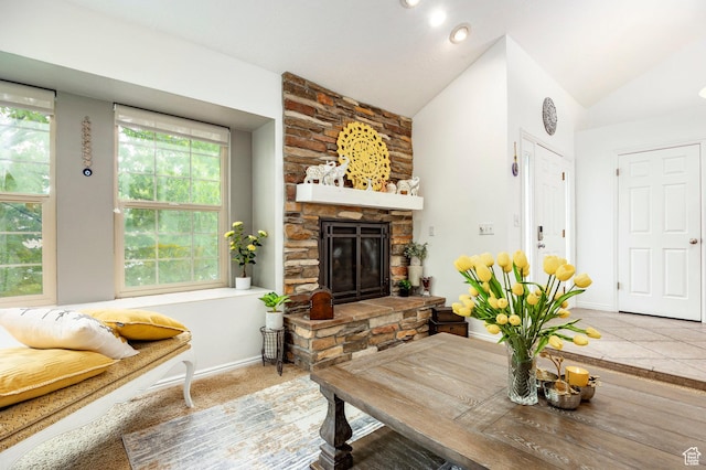 living area with a stone fireplace, lofted ceiling, and baseboards