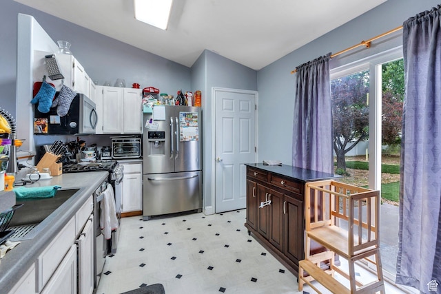 606 N 560 W, Santaquin, UT 84655 - kitchen with appliances with stainless steel finishes, light floors, white cabinetry, dark countertops, and lofted ceiling