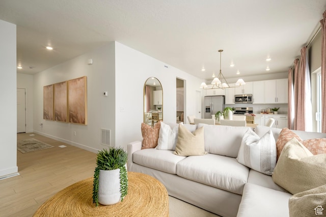 living area featuring a chandelier, light wood-style floors, recessed lighting, and baseboards