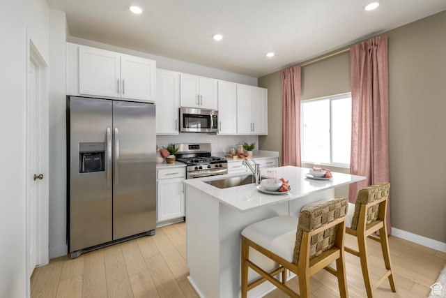 kitchen featuring stainless steel appliances, a sink, a center island with sink, light wood-style floors, and recessed lighting