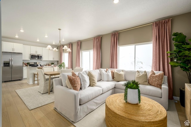living area featuring a chandelier, light wood-style flooring, and recessed lighting