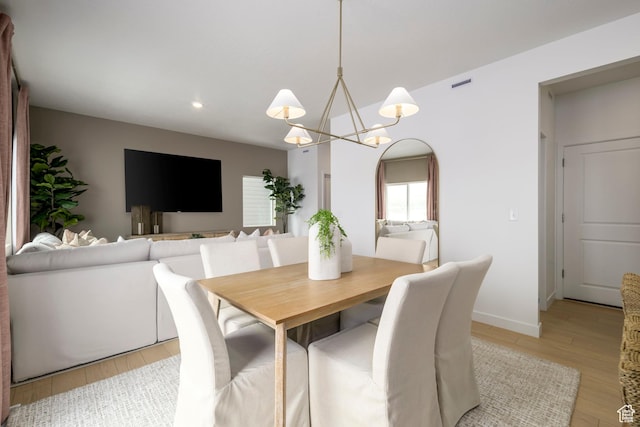 dining room with light wood-style flooring, arched walkways, recessed lighting, a chandelier, and baseboards