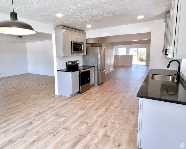 45 E 300 N, Roosevelt, UT 84066 - kitchen featuring stainless steel appliances, dark countertops, open floor plan, light wood finished floors, and a textured ceiling