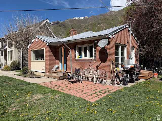 ranch-style house with a chimney, a front lawn, a mountain view, and metal roof