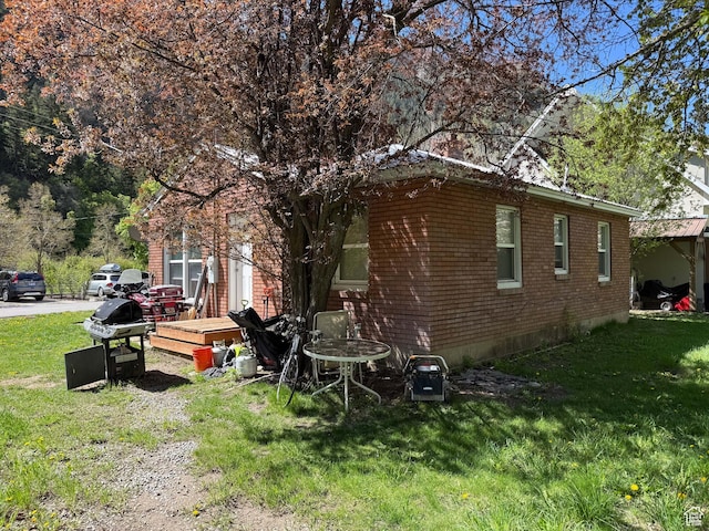 view of home's exterior featuring a wooden deck, a yard, and brick siding